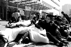 昨日，商戶們坐在春平購(gòu)物廣場(chǎng)門口的地鋪上。該商城關(guān)張數(shù)月，百余商戶索要事先交納的租金未果。本報(bào)記者 孫純霞 攝