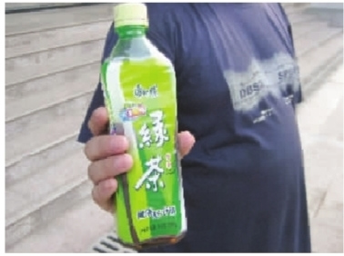 周先生拿著內(nèi)含黃色不明沉淀物的半瓶康師傅綠茶。 周先生拿著內(nèi)含黃色不明沉淀物的半瓶康師傅綠茶。